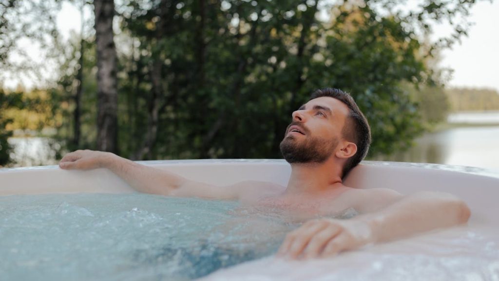 Bearded man unwinding in an outdoor hot tub surrounded by nature.